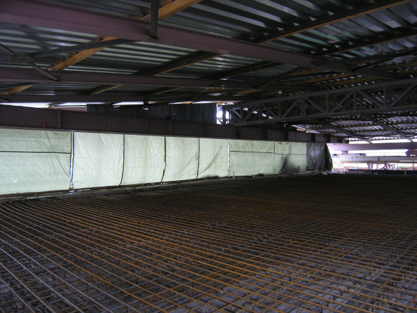 Výztuž zmonolitňující desky stropu překrytá při dešti pojízdnou halou